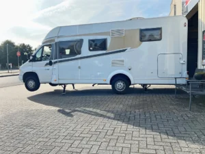 Witte camper die volledig en veilig van de grond wordt getild door het krachtige Campexx levelsysteem, ideaal voor bijvoorbeeld het wisselen van een band.