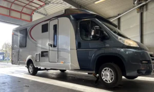 Een Fiat Ducato half-integraal camper die perfect stabiel op zijn uitgeschoven steunpoten staat in de HTW Camperservice garage.